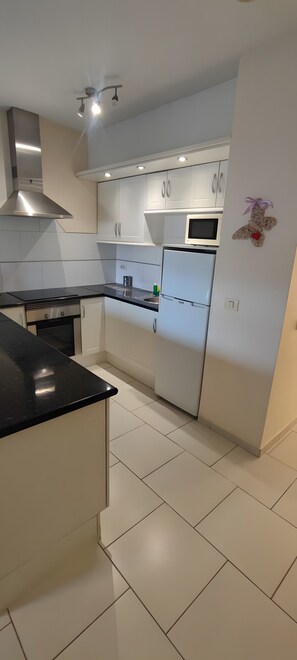A modern kitchen with white cabinetry, a black countertop, and stainless steel appliances. - Vacation Apartment 'Vacanze Mareverde' with Mountain View, Shared Pool and Wi-Fi (Costa Adeje)