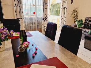 A dining area with a table set for two, a bottle of wine, and a vase with flowers. - Vacation Apartment 'Vacanze Mareverde' with Mountain View, Shared Pool and Wi-Fi (Costa Adeje)