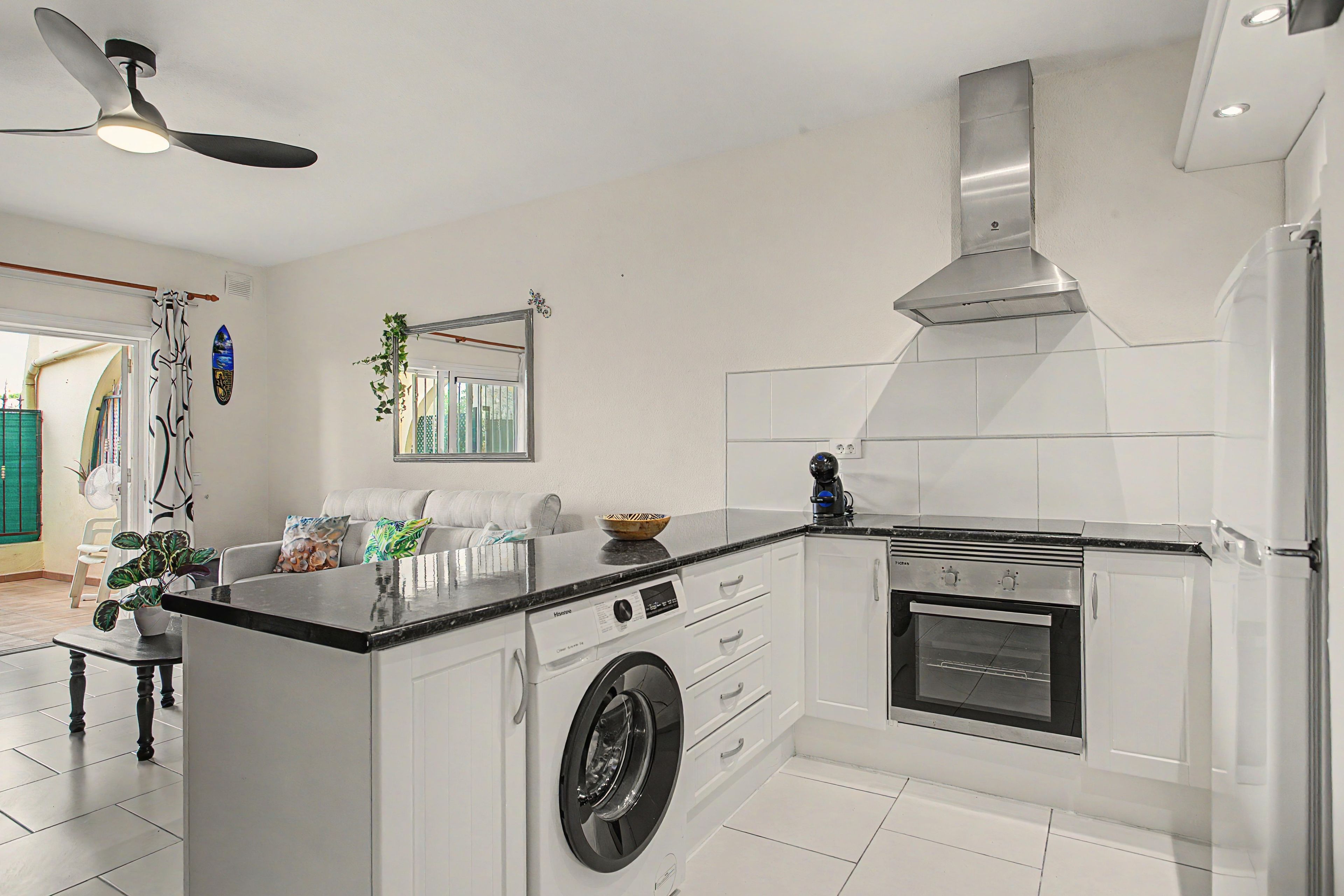 A modern kitchen with a built-in washing machine, a stove, and a ceiling fan.