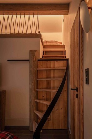 Eine Holztreppe mit schwarzer Handläufe, die zu einer Zwischenebene führt.