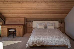 A bedroom with a wooden ceiling, a bed with floral bedding, a desk with a chair, and a small stool. - Chalet Fleur des Vosges, panoramic view of La Bresse (La Bresse)