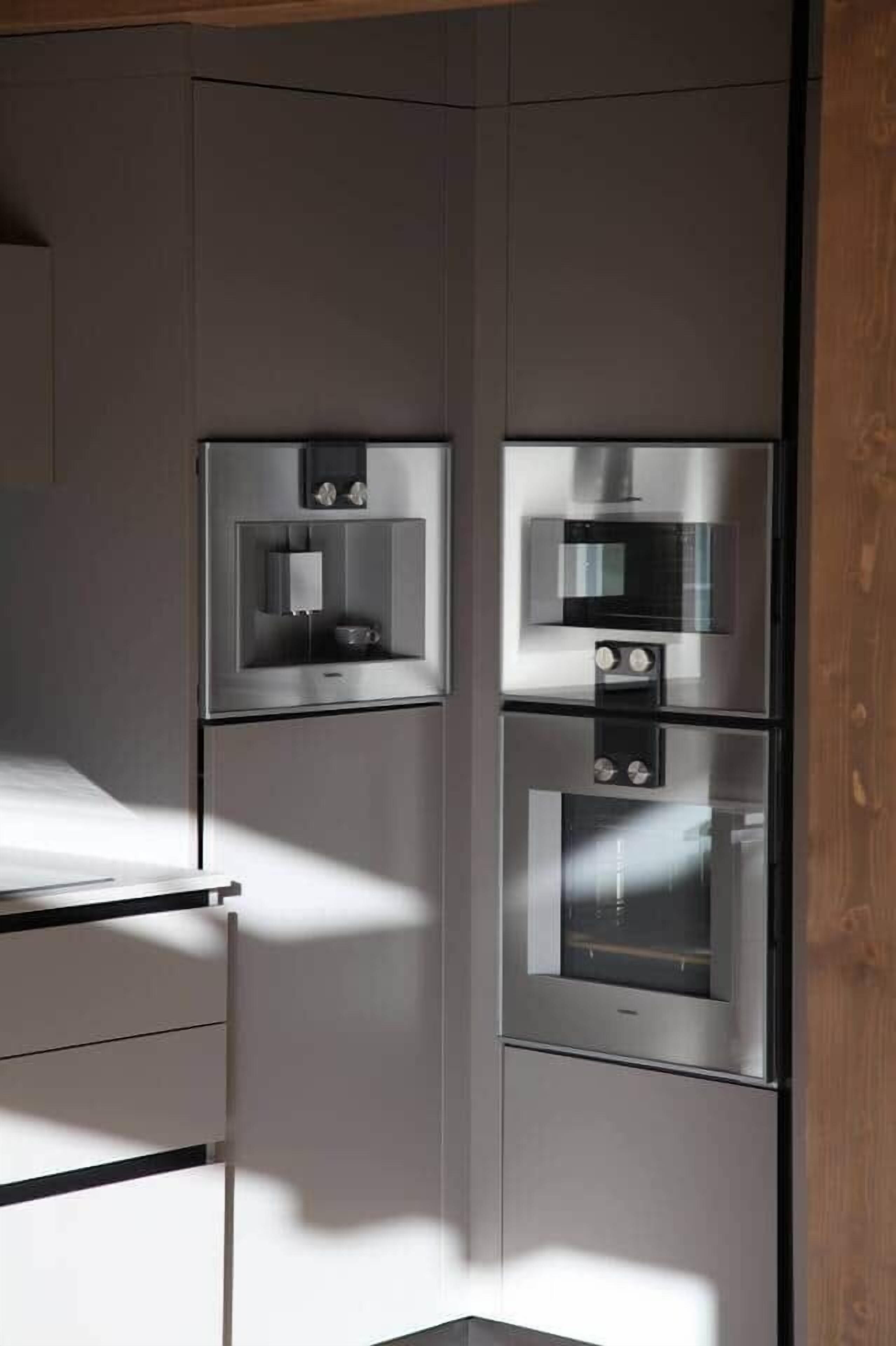 A modern kitchen with built-in appliances, including a microwave, oven, and a small refrigerator.