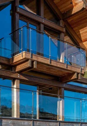 Een meerlaagse houten constructie met glazen hekwerk.