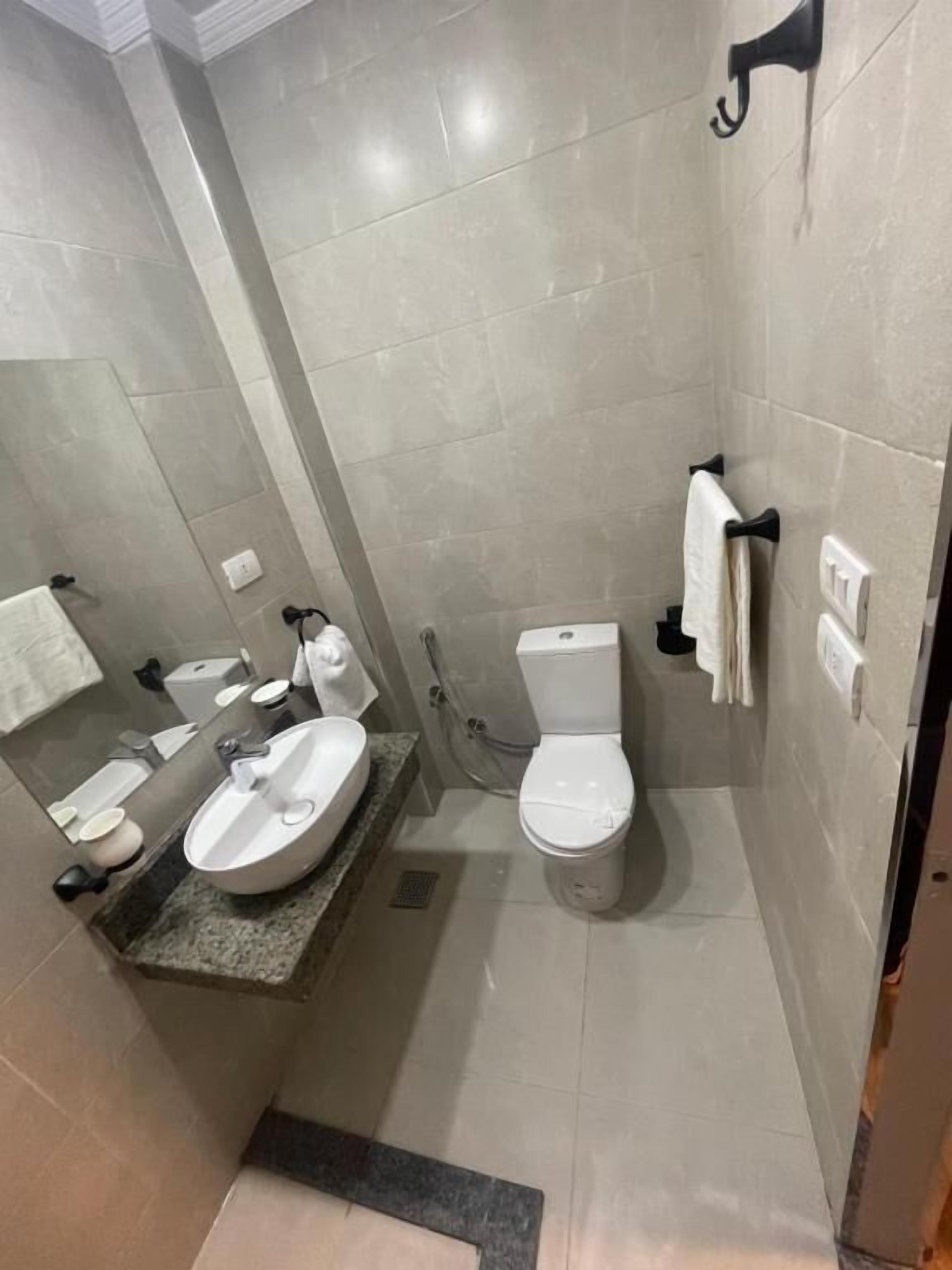 A bathroom with a sink, toilet, and towel rack.