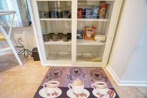 A kitchen with a coffee station featuring a coffee maker, cups, and a coffee bean bag. - Bright Horizons Hideaway w/POOL- 18 min to MAYO (Jacksonville)