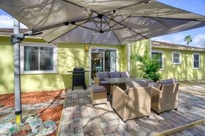 An outdoor patio with a table and chairs, a grill, and a covered area with an umbrella. - Bright Horizons Hideaway w/POOL- 18 min to MAYO (Jacksonville)