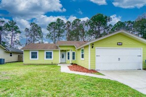 A single-story house with a front garage, a small porch, and a well-maintained lawn. - Bright Horizons Hideaway w/POOL- 18 min to MAYO (Jacksonville)
