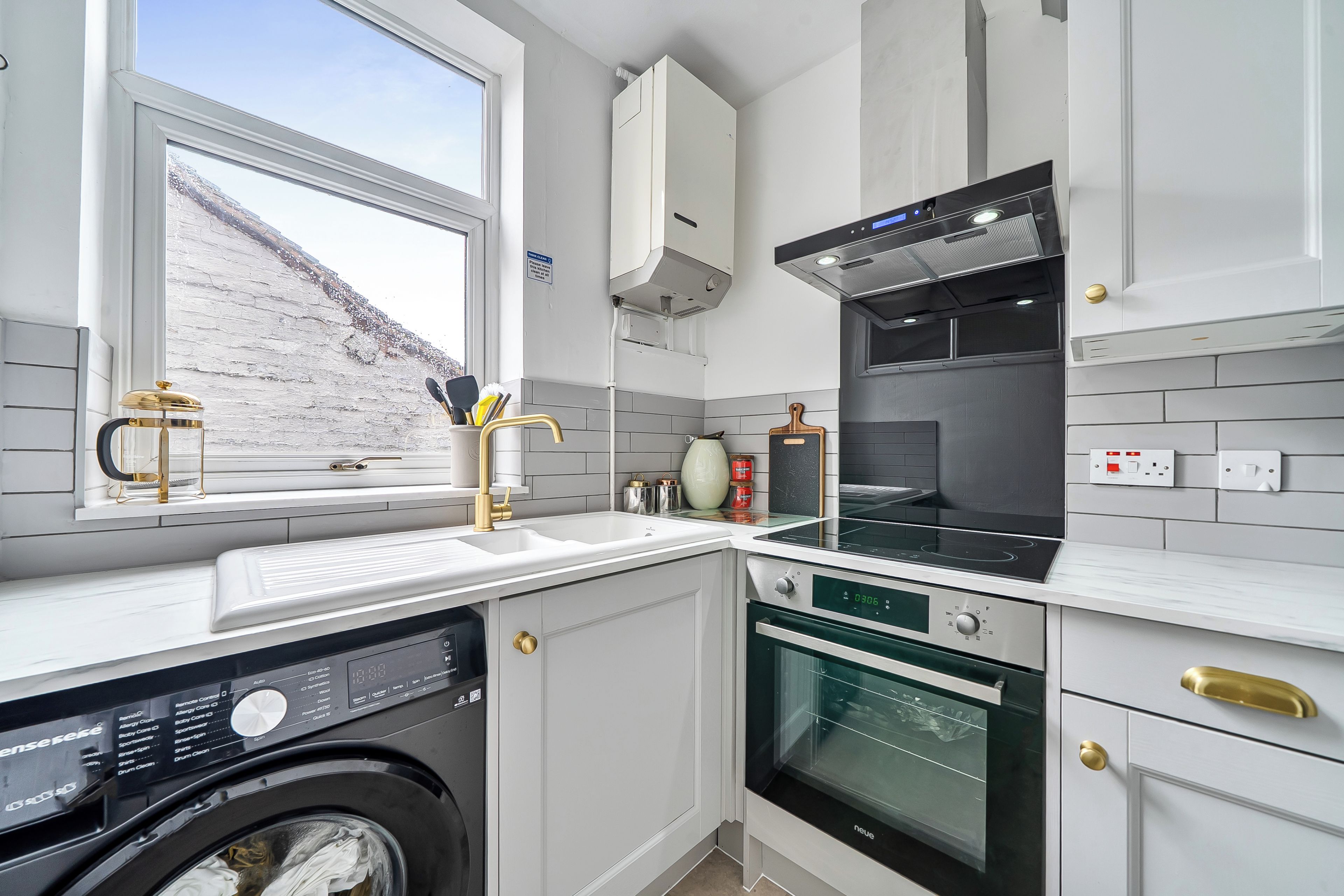 A modern kitchen with a built-in washing machine, a stove, and a microwave.