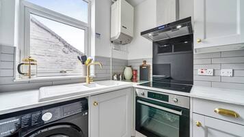 A modern kitchen with a built-in washing machine, a stove, and a microwave.
