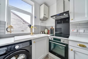 Moderni keittiö, jossa on sisäänrakennettu pesukone, liesi ja mikroaaltouuni.