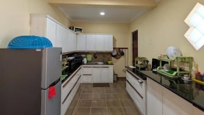 Cocina con armarios blancos, un refrigerador y piso de baldosas.