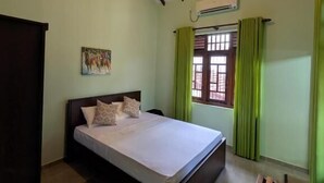 Un dormitorio con una cama, un banco de madera, una ventana con cortinas y un ventilador de techo.