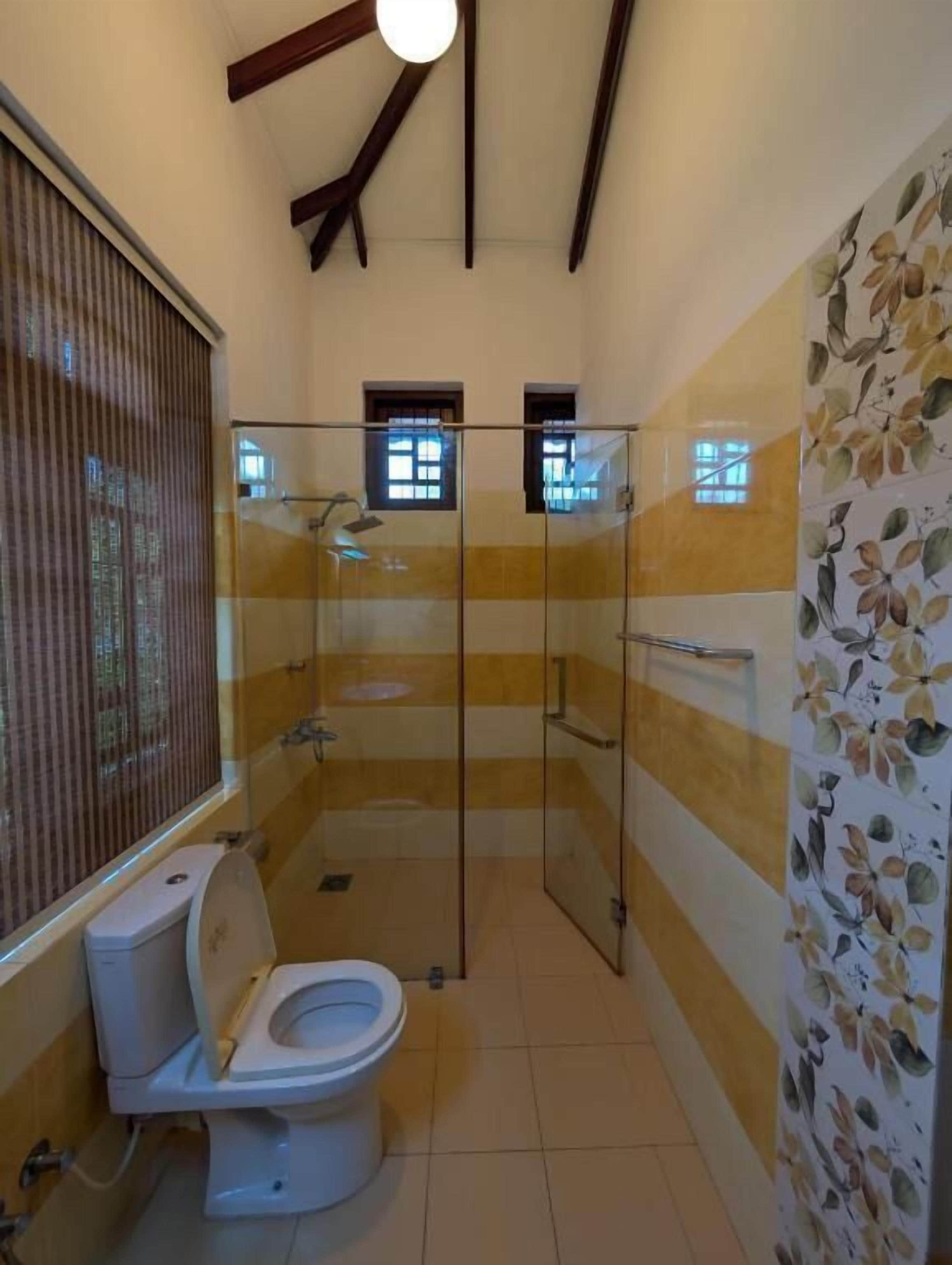 Un baño con inodoro, cabina de ducha y ventana.
