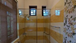 Un baño con inodoro, cabina de ducha y ventana.