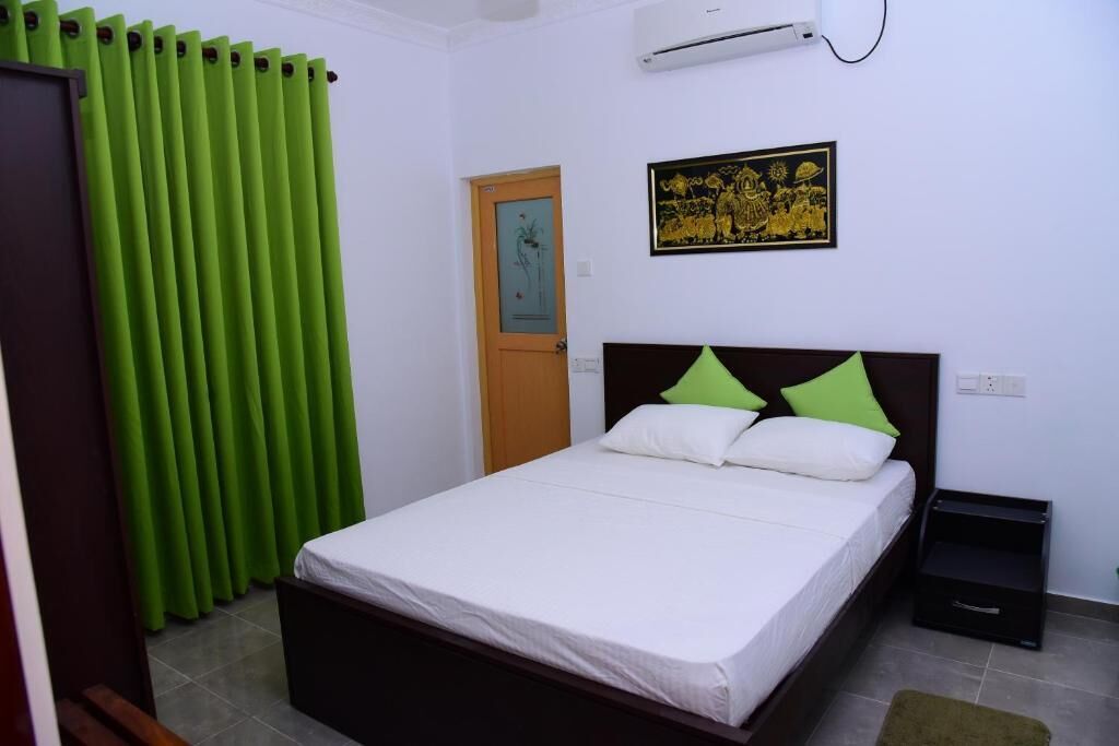 Un dormitorio con cama, mesita de noche, puerta y aire acondicionado instalado en la pared.