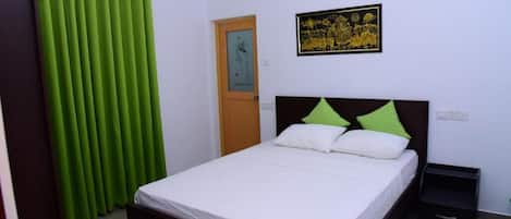 A bedroom with a bed, a nightstand, a door, and a wall-mounted air conditioning unit.