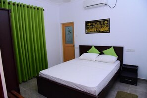 Une chambre à coucher comprenant un lit, une table de chevet, une porte et un climatiseur fixé au mur.
