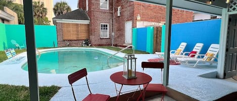 Un espace extérieur abrité comprenant une piscine, des chaises rouges et une table.