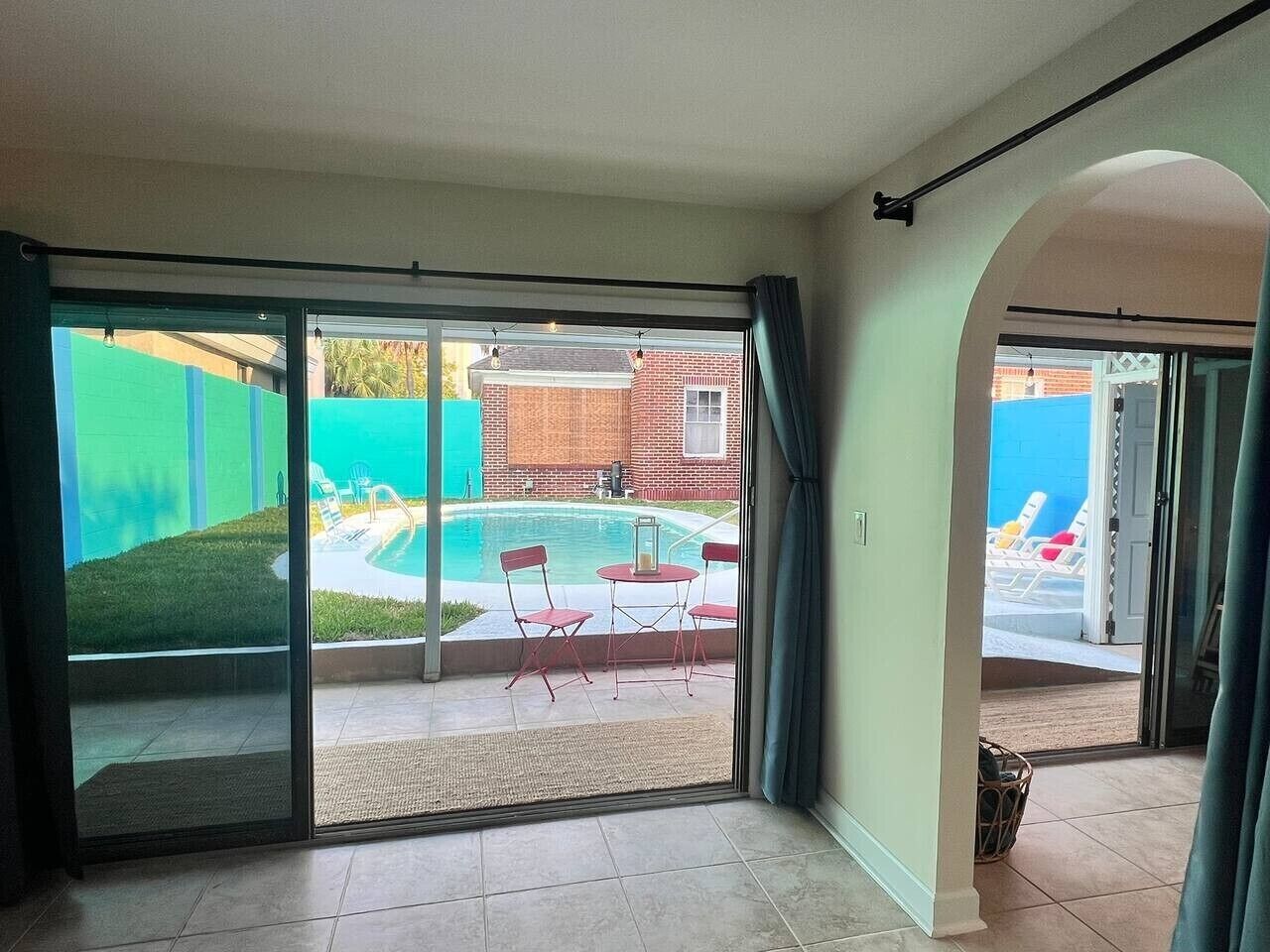 A room with a sliding glass door leading to a backyard with a swimming pool, a small table, and two chairs.