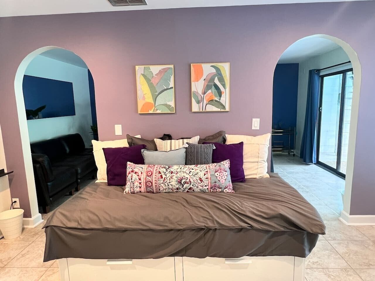 Un dormitorio con una cama grande, varios almohadones y dos cuadros colgados en la pared.