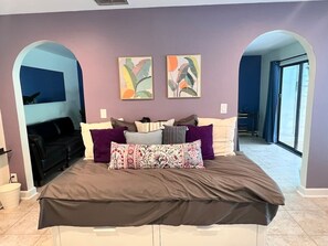 Une chambre à coucher avec un grand lit, de nombreux oreillers et deux tableaux accrochés au mur.