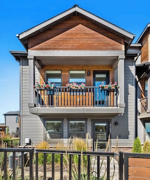 A two-story house with a balcony, large windows, and a wooden facade.