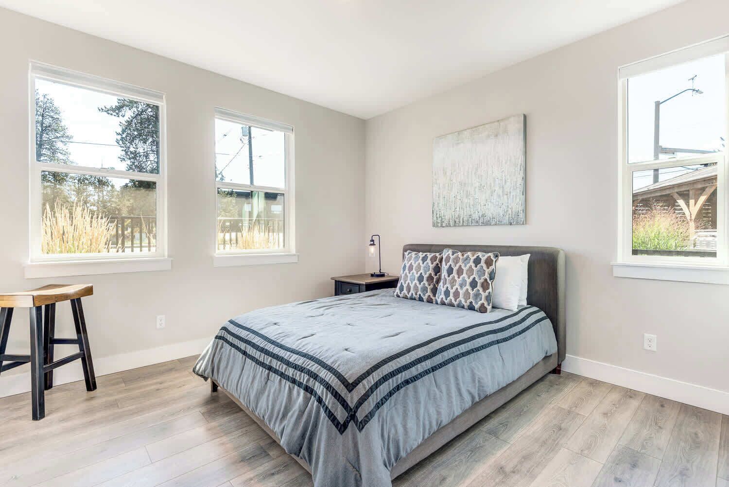A bedroom with a bed, a nightstand, a lamp, and a window with a view of trees.
