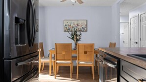 A kitchen with a refrigerator, wooden chairs, a dining table, and a ceiling fan. - San Pablo Retreat Near Mayo Clinic Mins to Beaches (Jacksonville)
