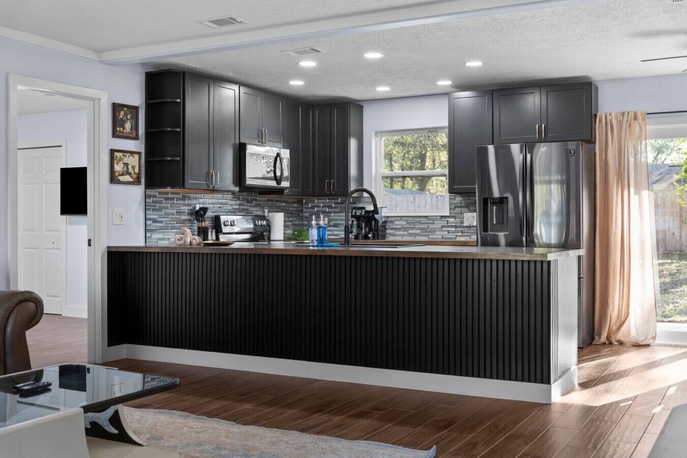 A modern kitchen with dark cabinetry, a central island, and a window providing natural light.