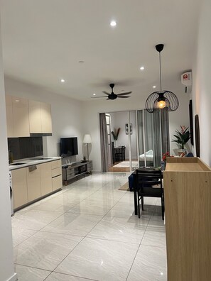 Una cocina moderna con un televisor de pantalla plana, un comedor con una mesa de madera y un ventilador de techo.