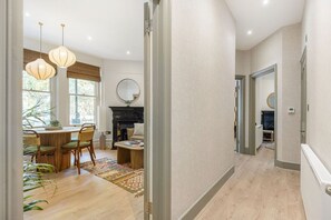 A spacious room with a dining area, a fireplace, and a mirror on the wall. - GuestReady - Charming London Retreat for Four (London)