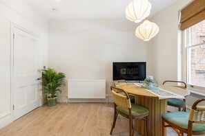 Uma sala de estar moderna com área de jantar, radiador, televisão e um vaso com planta.