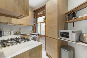 Cozinha compacta com fogão a gás, máquina de lavar e micro-ondas.