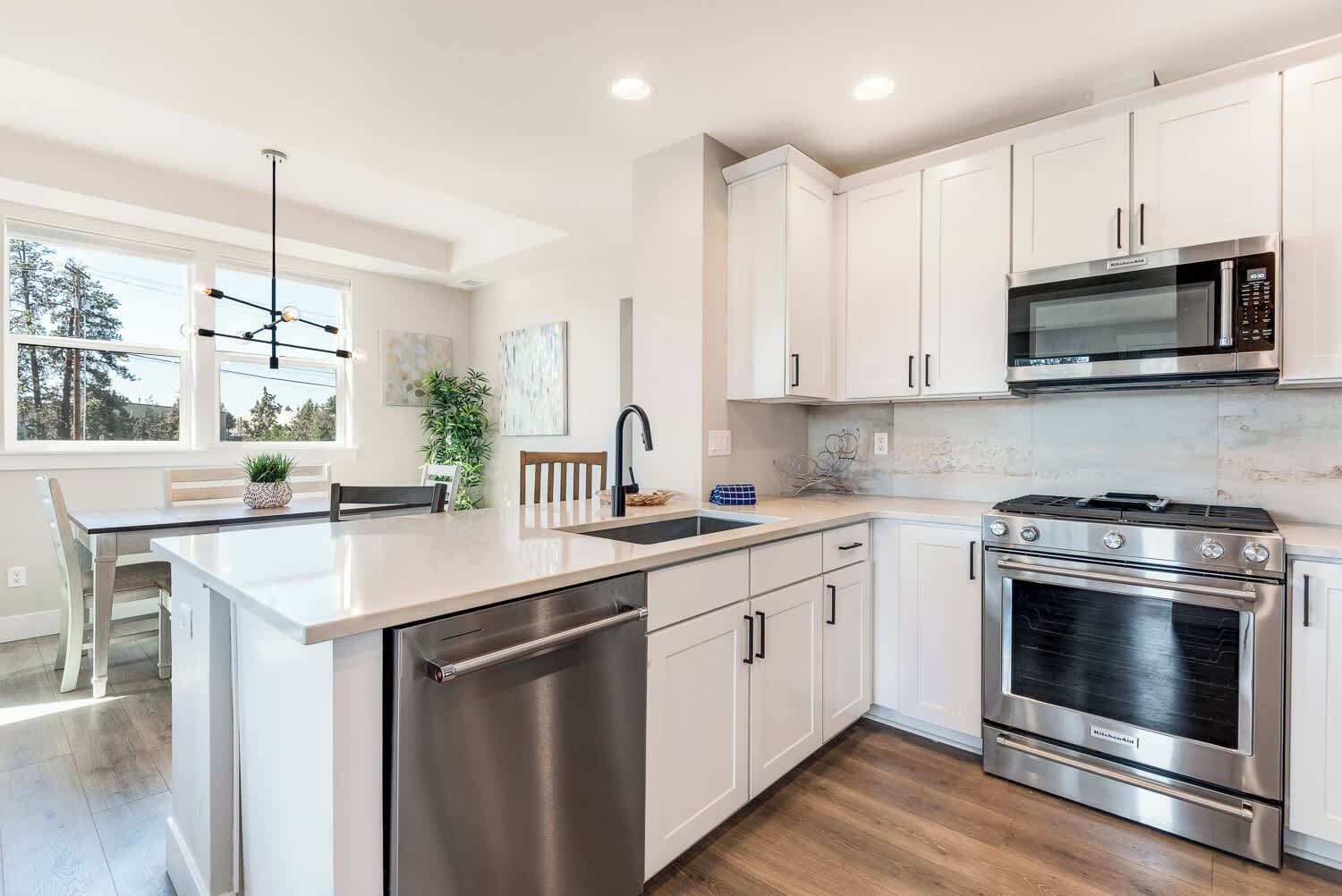 A modern kitchen with white cabinetry, stainless steel appliances, and a central island with a dishwasher.