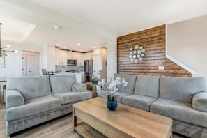 A modern living room with two grey sofas, a wooden coffee table, and a decorative wall with circular mirrors.