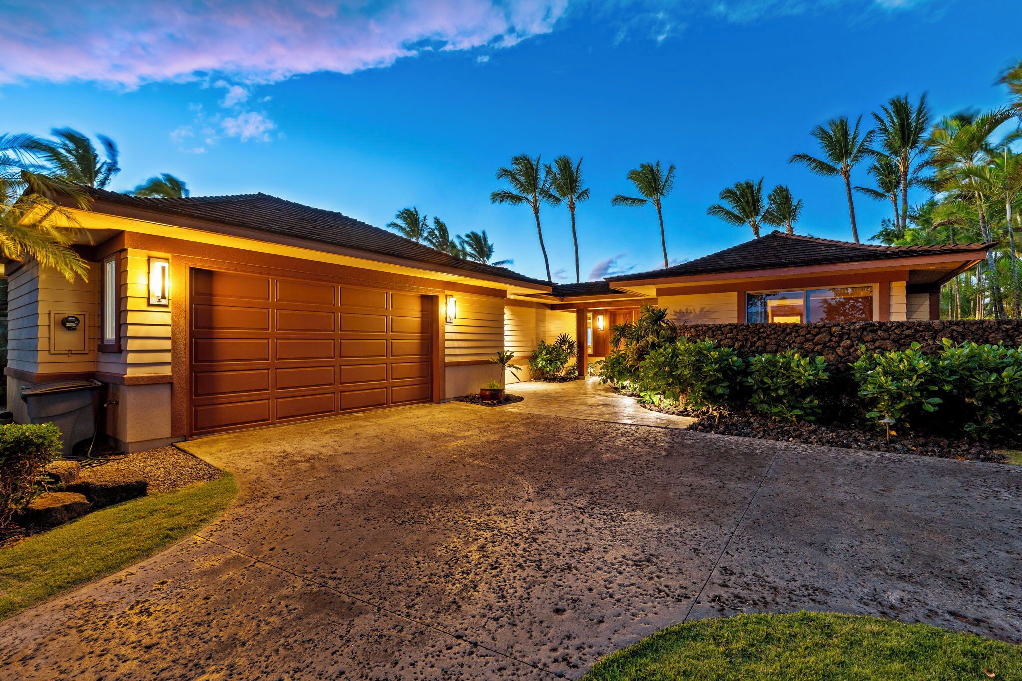 A two-story house with a garage, a driveway, and a well-maintained lawn.