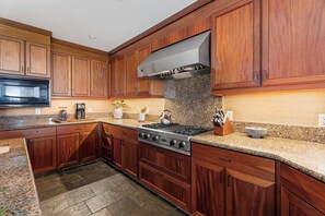 A kitchen with wooden cabinets, a stainless steel stove, granite countertops, and a microwave. - Pakui Street Estate by Gather - Hualalai Golf Estate w/ Private Pool & Spa (Kailua Kona)