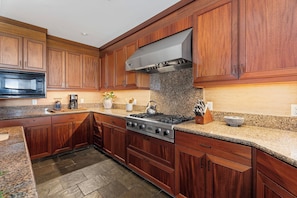 A kitchen with wooden cabinets, a stainless steel stove, granite countertops, and a microwave. - Pakui Street Estate by Gather - Hualalai Golf Estate w/ Private Pool & Spa (Kailua Kona)