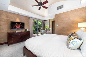 A bedroom with a large bed, a television on a wooden dresser, and a ceiling fan. - Pakui Street Estate by Gather - Hualalai Golf Estate w/ Private Pool & Spa (Kailua Kona)
