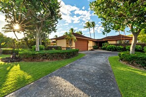 A residential property with a driveway leading to a house, surrounded by lush greenery and palm trees. - Pakui Street Estate by Gather - Hualalai Golf Estate w/ Private Pool & Spa (Kailua Kona)