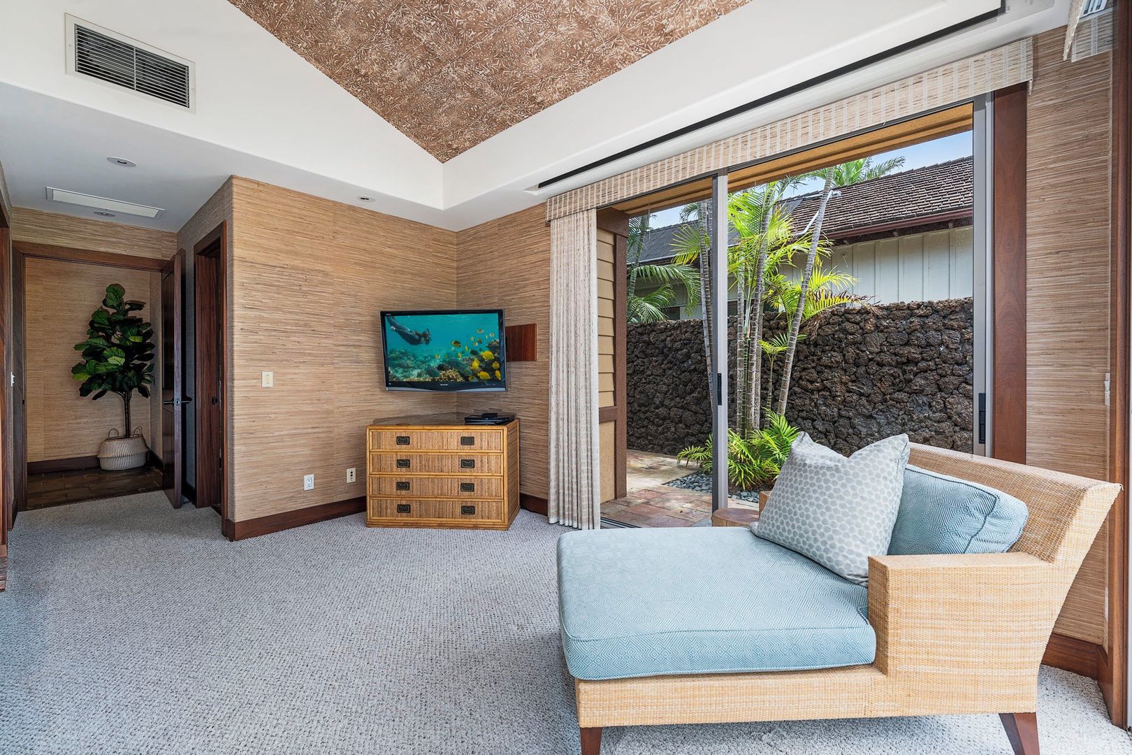 A modern living room with a television, a sofa, and a view of the outdoors.