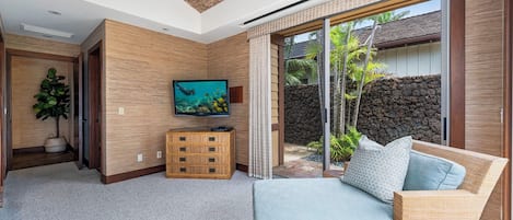 Una sala de estar moderna con televisor, sofá y vistas al exterior.