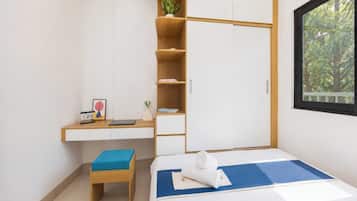 A bedroom with a bed, a desk, a chair, a wardrobe, and a window.