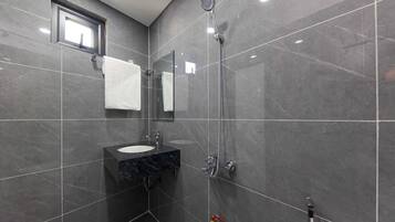 A modern bathroom with a sink, mirror, and shower.