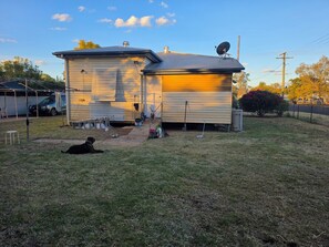 A two-story house with a satellite dish, a garage, and a dog lying on the grass.