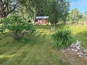 A red house with a well-maintained lawn, a bird bath, and a statue of a rabbit.