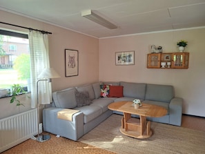 A living room with a grey sofa, a wooden coffee table, a floor lamp, and a radiator.