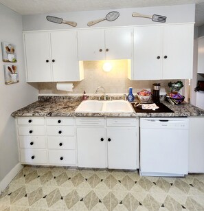 A kitchen with white cabinets, a granite countertop, a built-in dishwasher, and a tiled floor. - Apartment with private patio overlooking golf course. Close to UNMC, VA Hospital (Omaha)