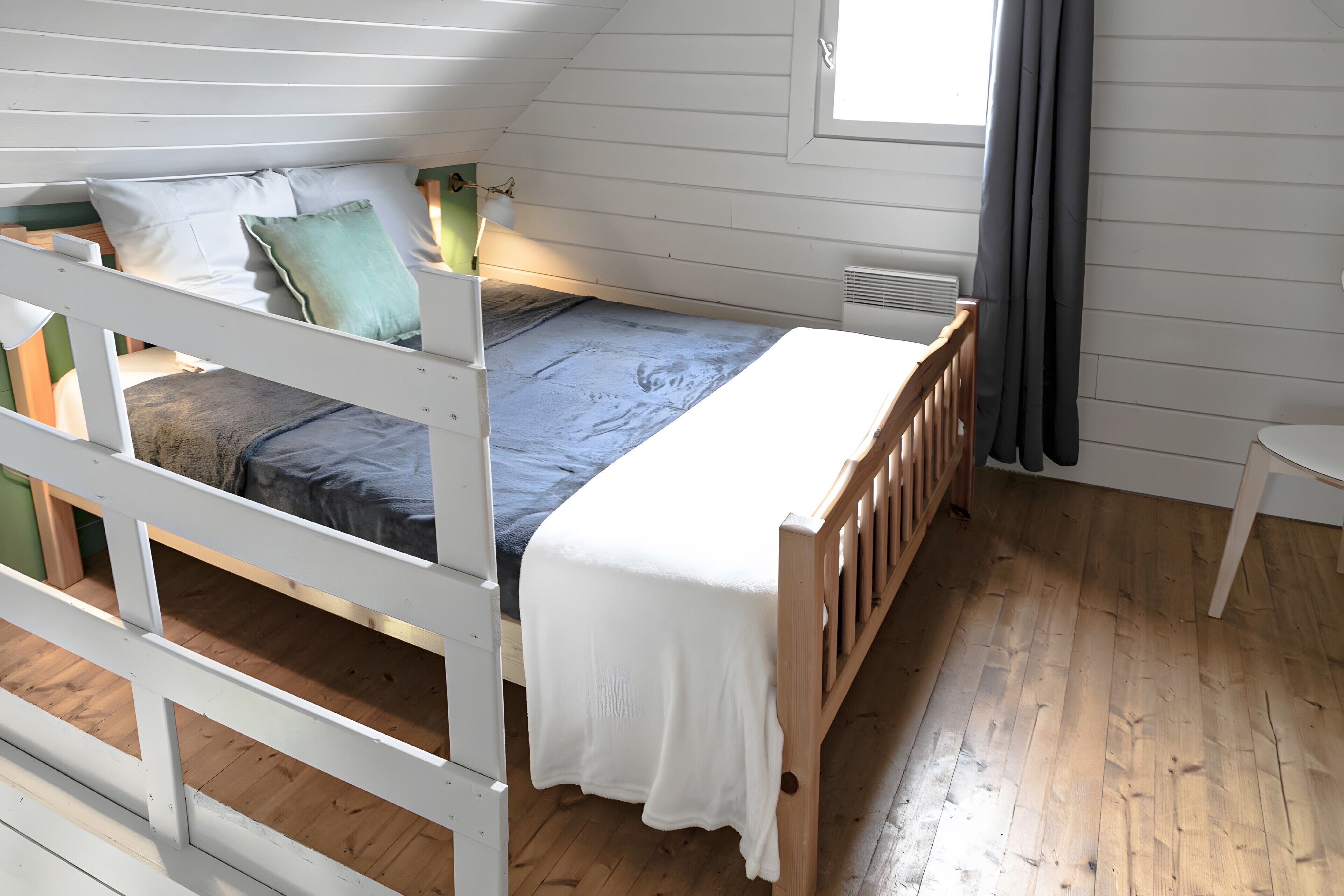 A single bed with a wooden frame, a headboard, and a footboard, with a window above it.