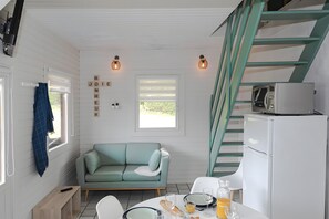 A compact kitchen with a teal sofa, a white refrigerator, and a dining table set for breakfast.